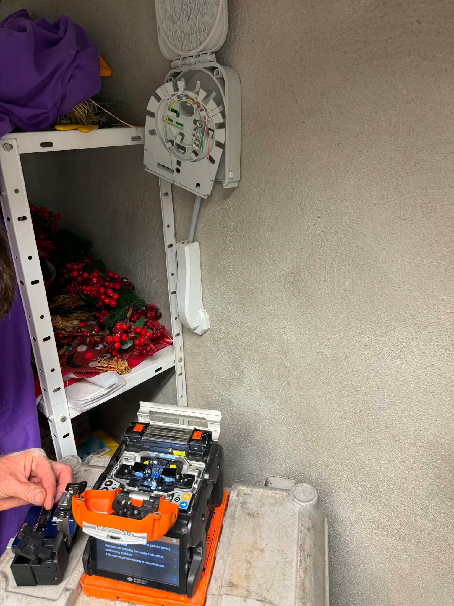 Spleissgeraet vor einer geoeffneten Glasfaser-Anschlussbox